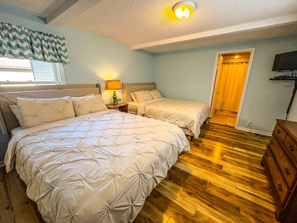 Un lit queen dans une chambre partagée à deux lits queen avec salle de bain partagée